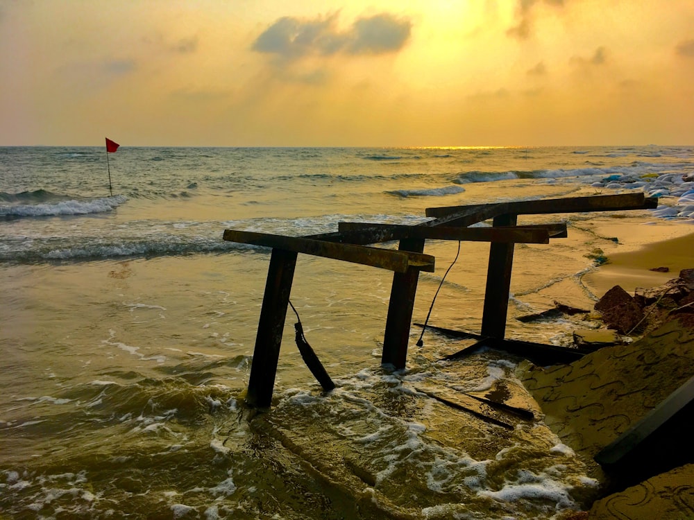 a wooden bench sitting on top of a beach next to the ocean