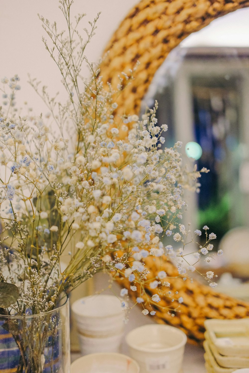 a vase filled with white flowers next to a mirror