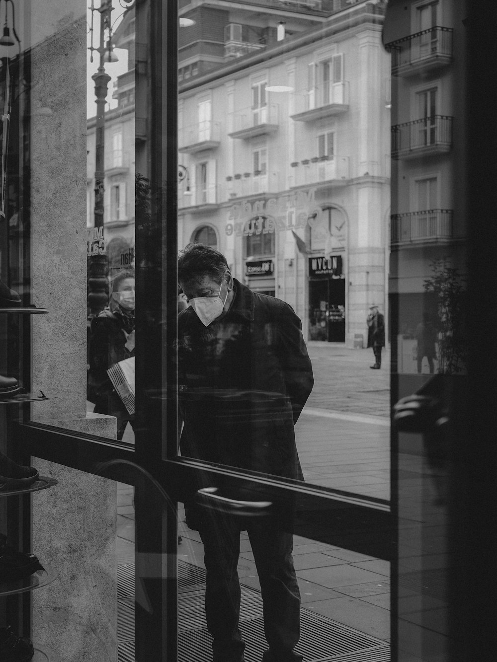 a man standing outside of a building looking in a window