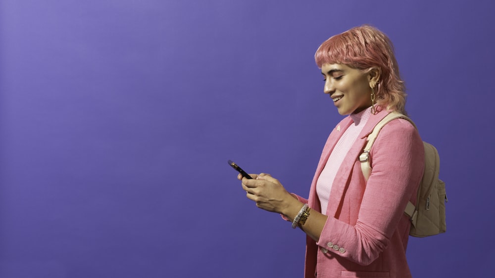 Une femme aux cheveux roses regarde son téléphone portable