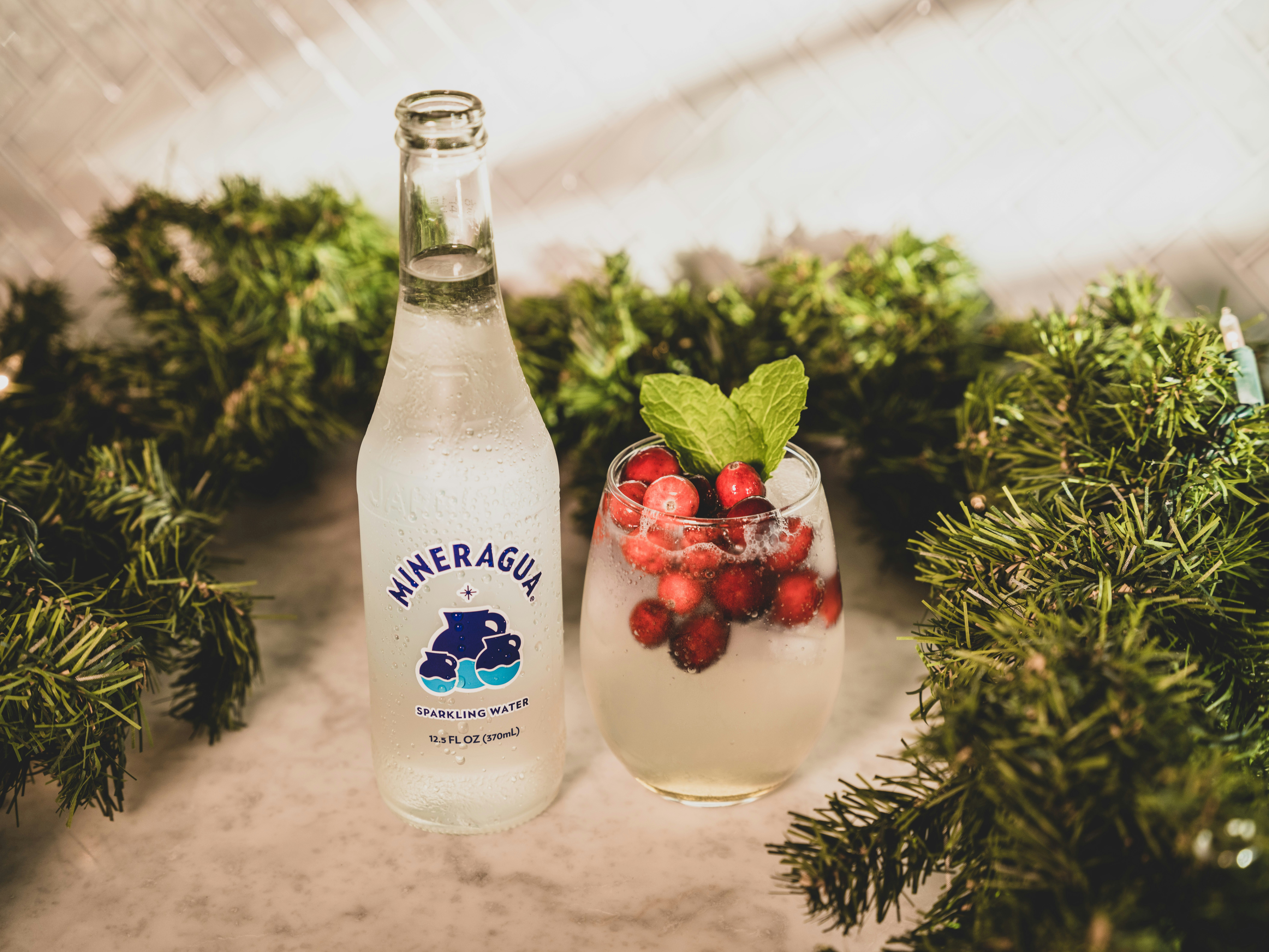 a bottle of mineral water next to a glass filled with berries