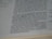 The close-up image displays a page of a book with text printed in black ink. The paper appears slightly off-white and lined margins are visible on the left side of the page. The photograph is focused more on the lower portion of the text, with some parts appearing slightly blurred.