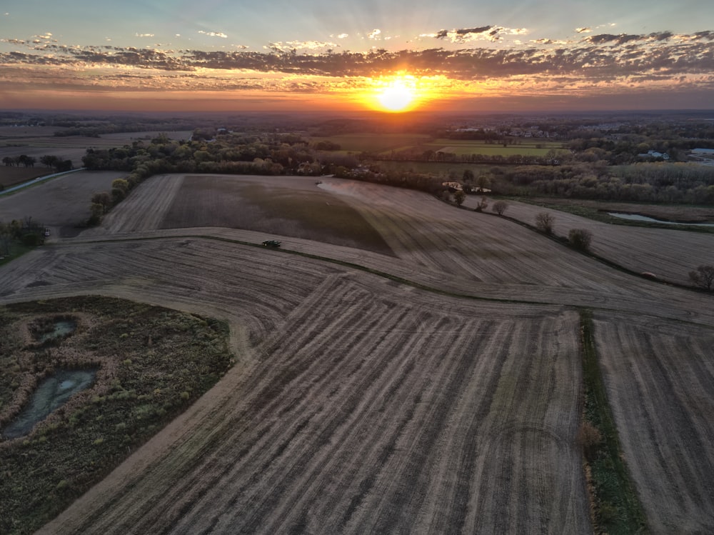 the sun is setting over a farm land