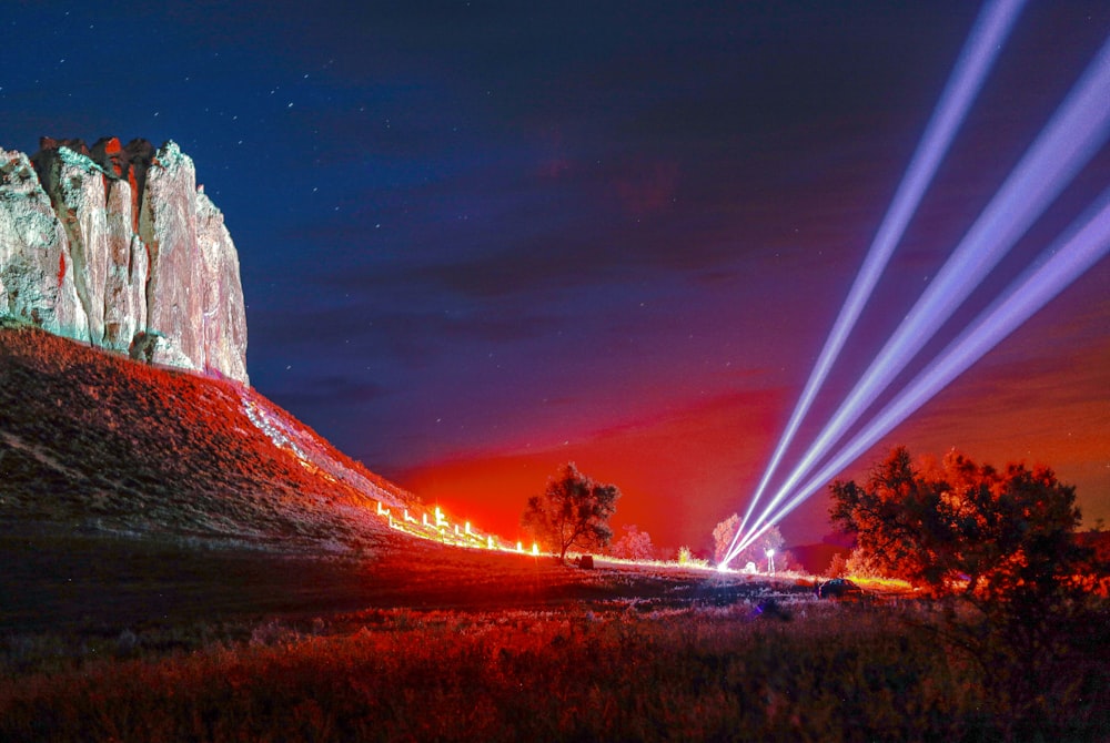 a night scene of a mountain with lights shining on it