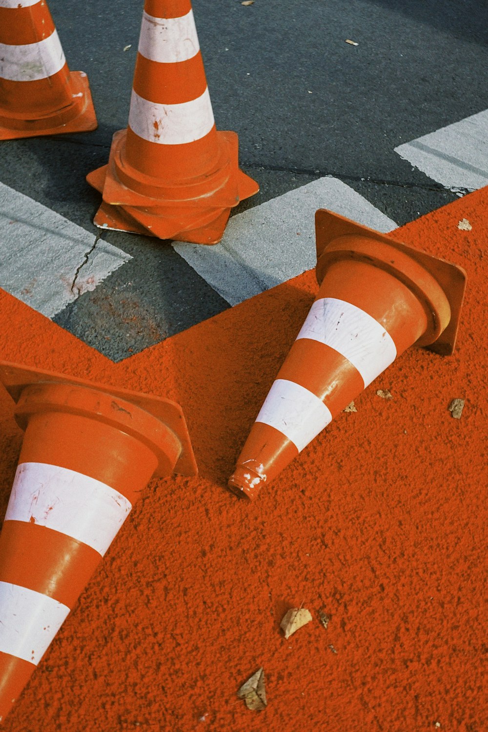 um grupo de cones alaranjados sentados ao lado de uma estrada