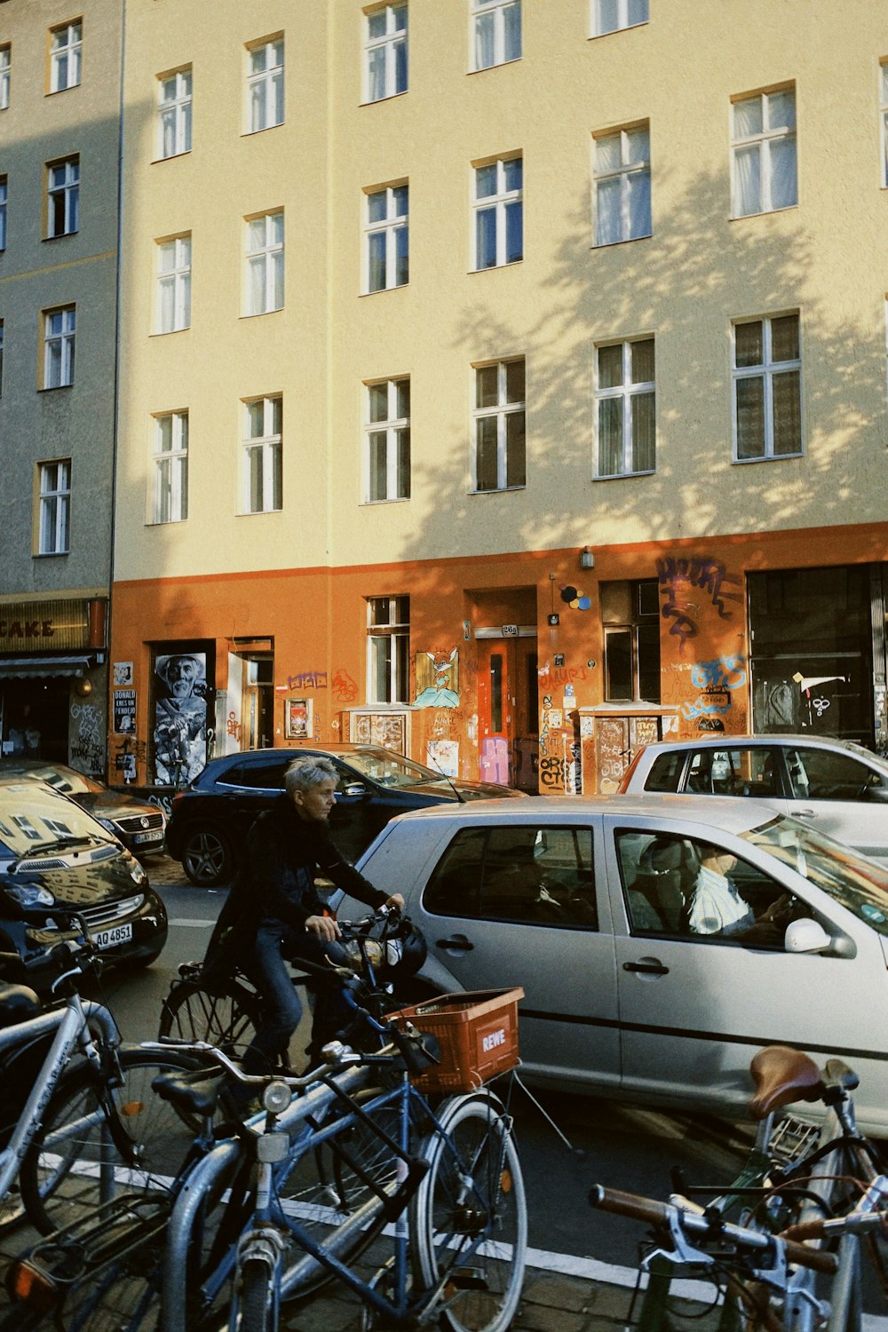 a man riding a bike down a street next to parked cars