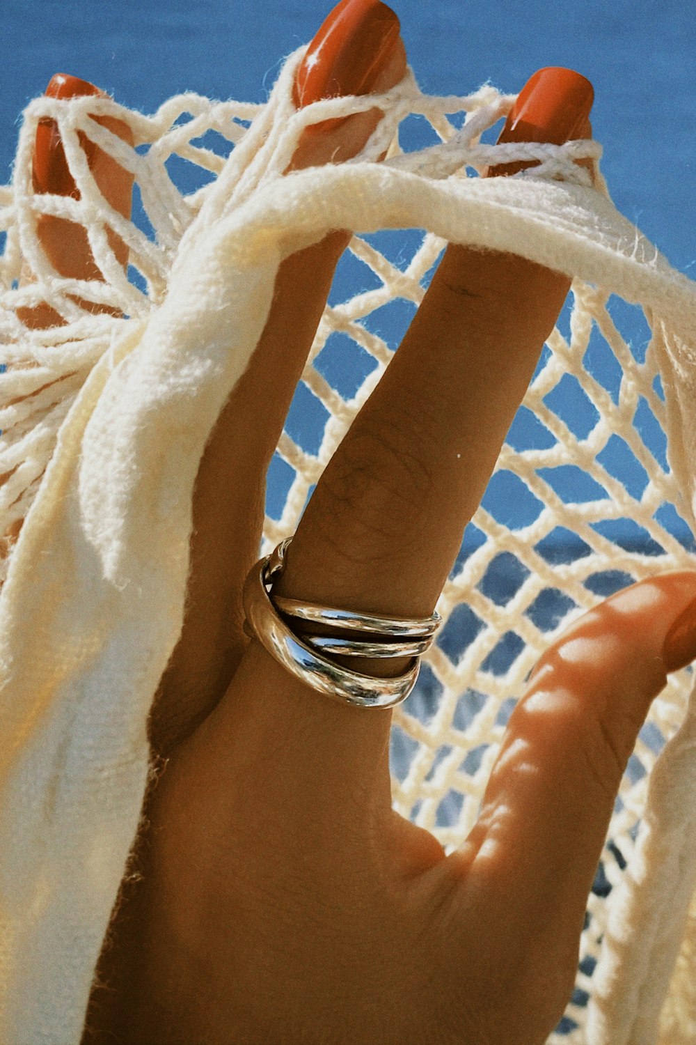 a woman's hand holding a ring in front of a white net