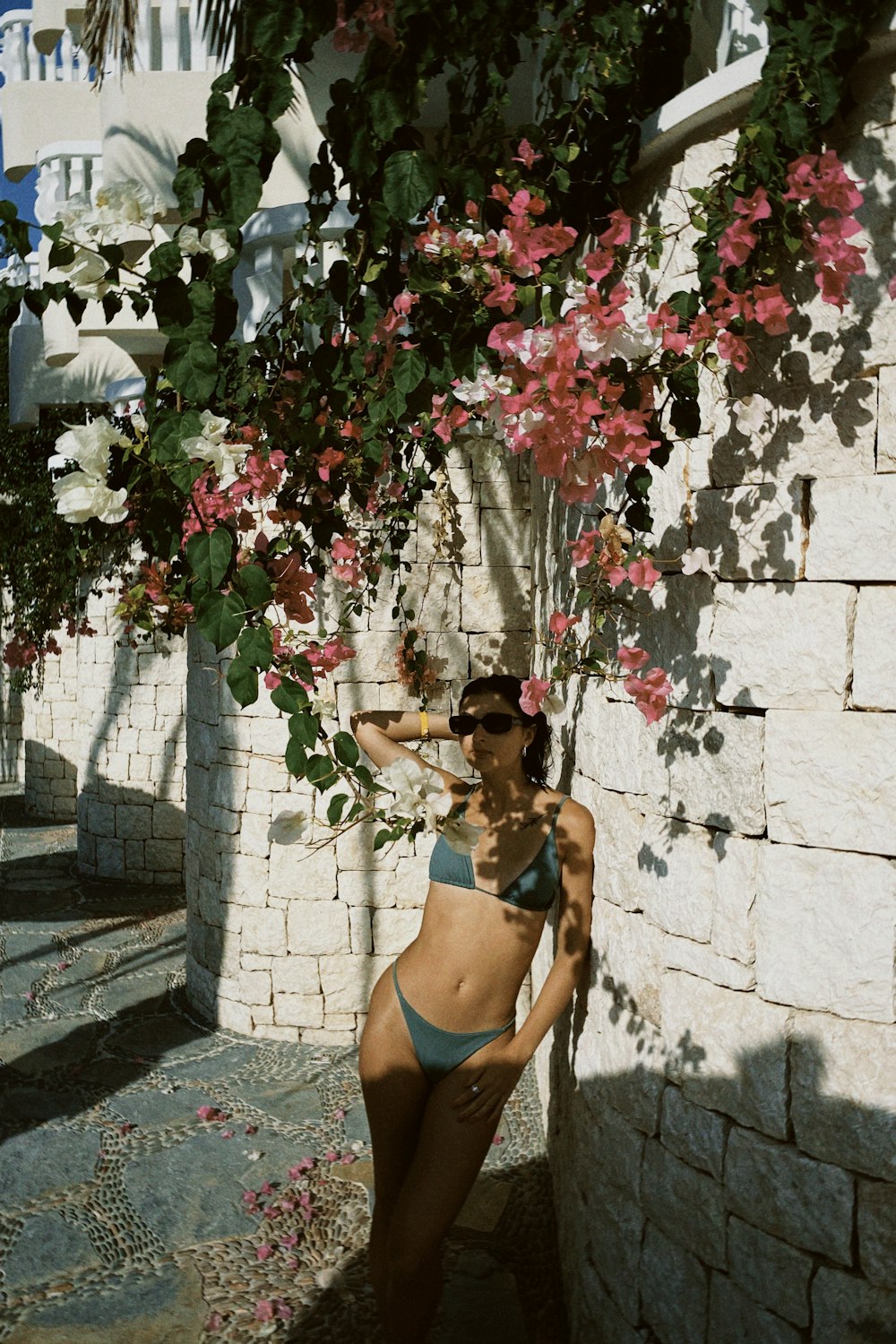 a woman in a bikini standing next to a stone wall