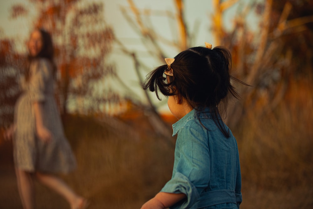 a little girl standing next to a woman in a field