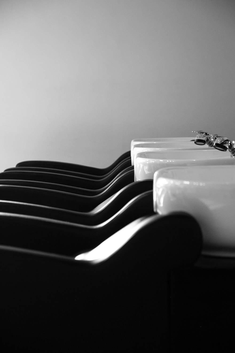 a black and white photo of a row of sinks