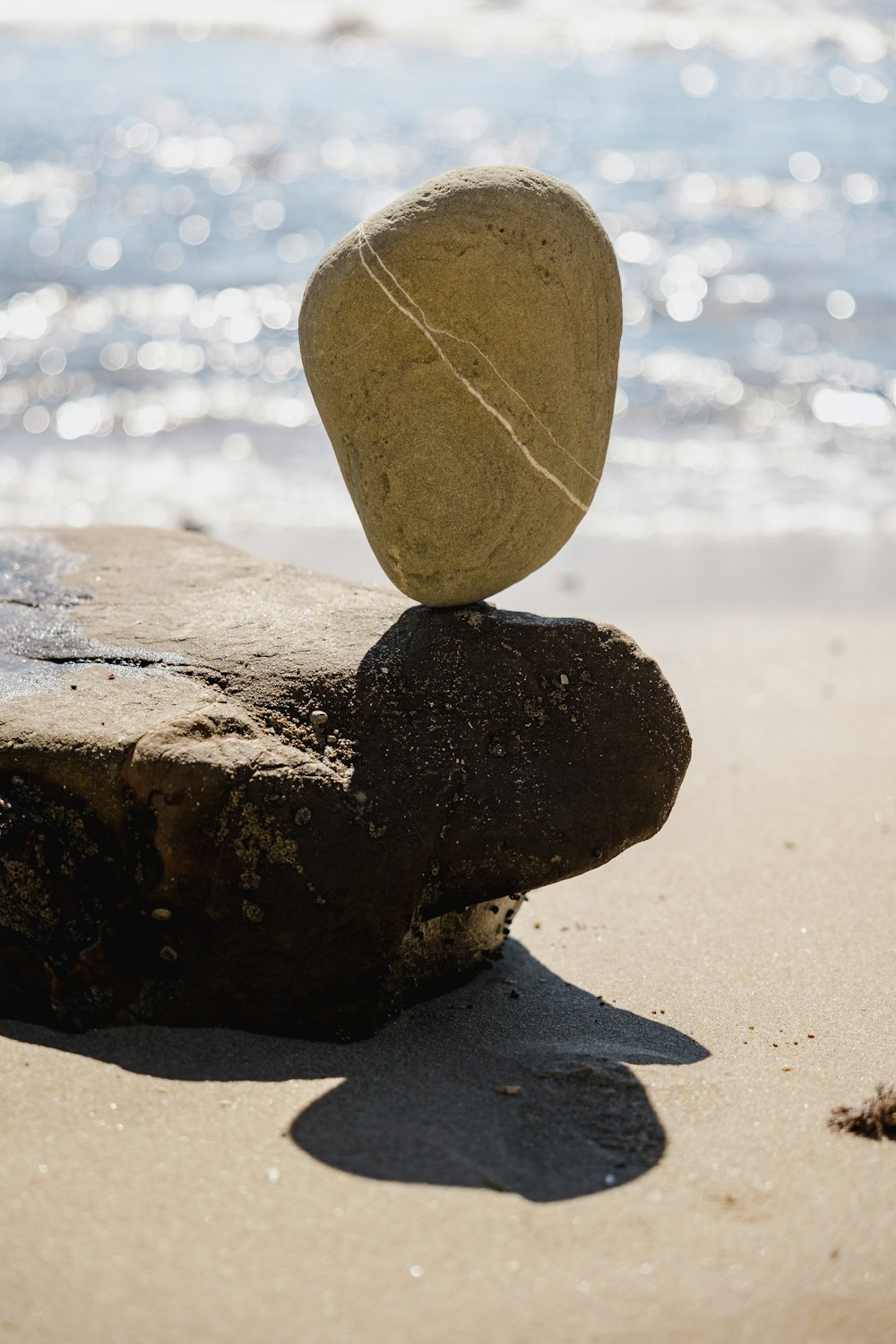 a rock balanced on top of another rock on the beach