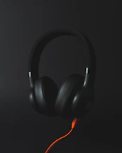 A sleek neon orange outline of a headset against a black background, symbolizing customer support.