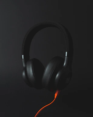 A sleek neon orange outline of a headset against a black background, symbolizing customer support.