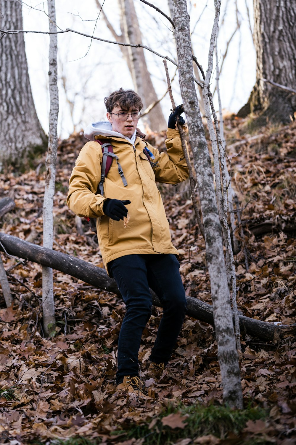 a man in a yellow jacket walking through a forest