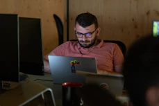 A focused middle-aged man watching an educational video on his laptop in a cozy room.