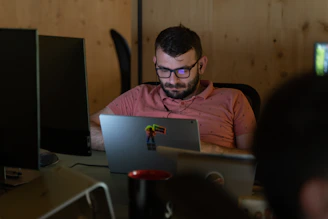 A focused professional working on a laptop with multiple screens showing business analytics in a cozy home office.