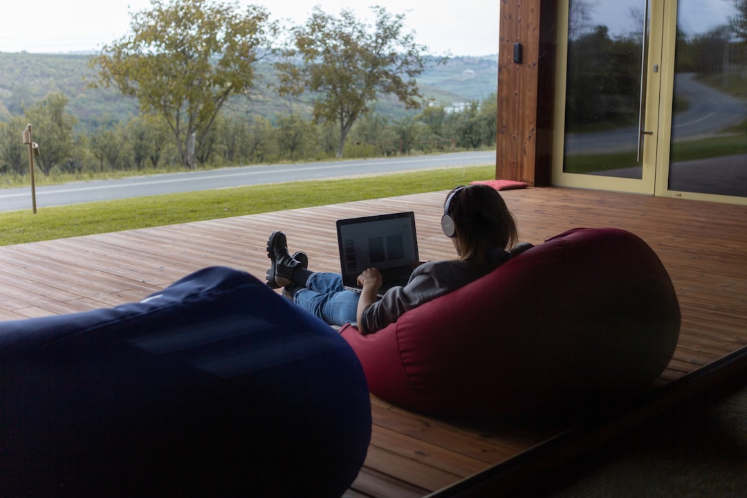 a person sitting on a bean bag chair using a laptop, Woman remote work outdoors