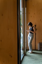 a woman standing in front of a door looking at her cell phone