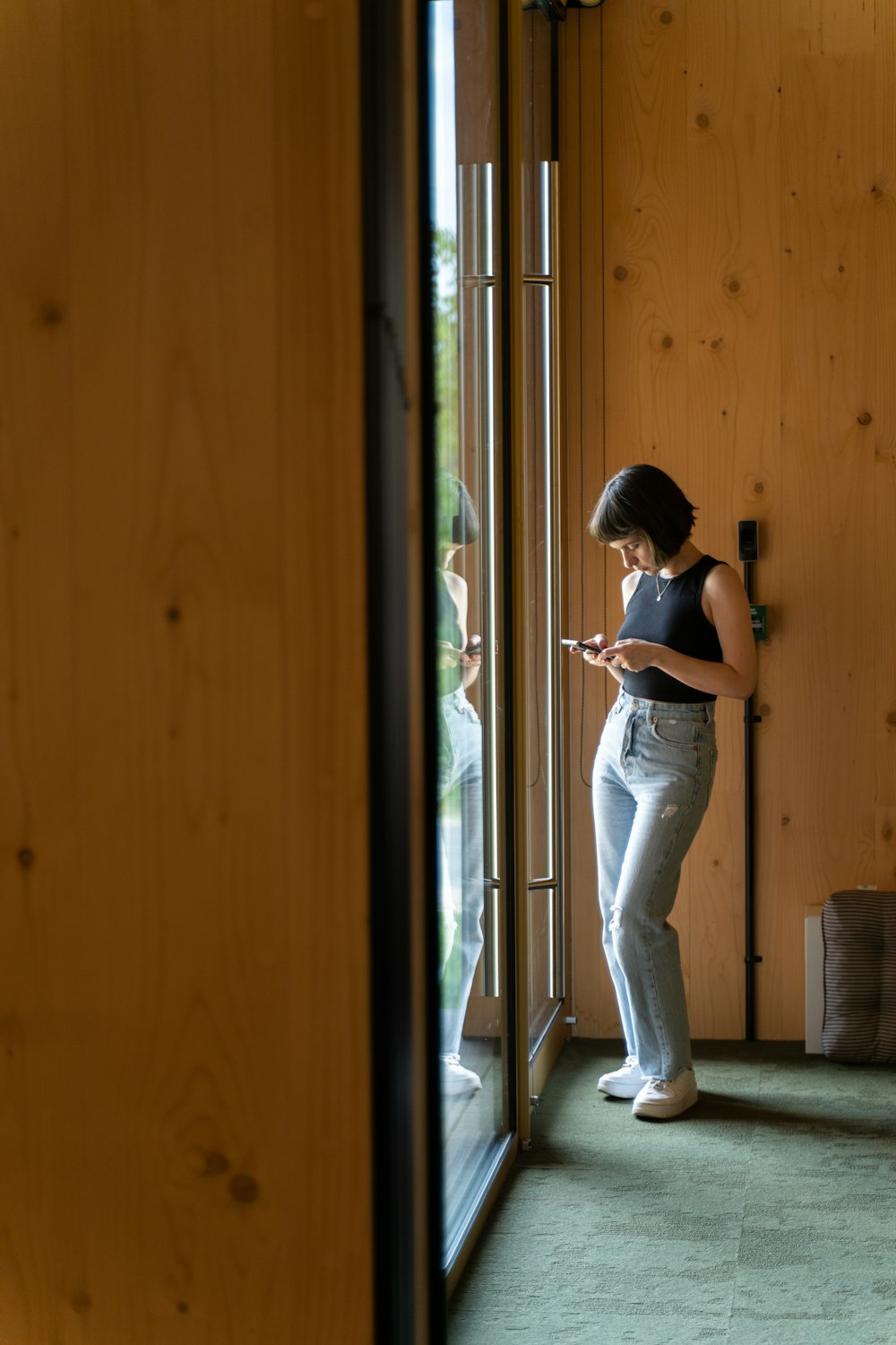 a woman standing in front of a door looking at her cell phone