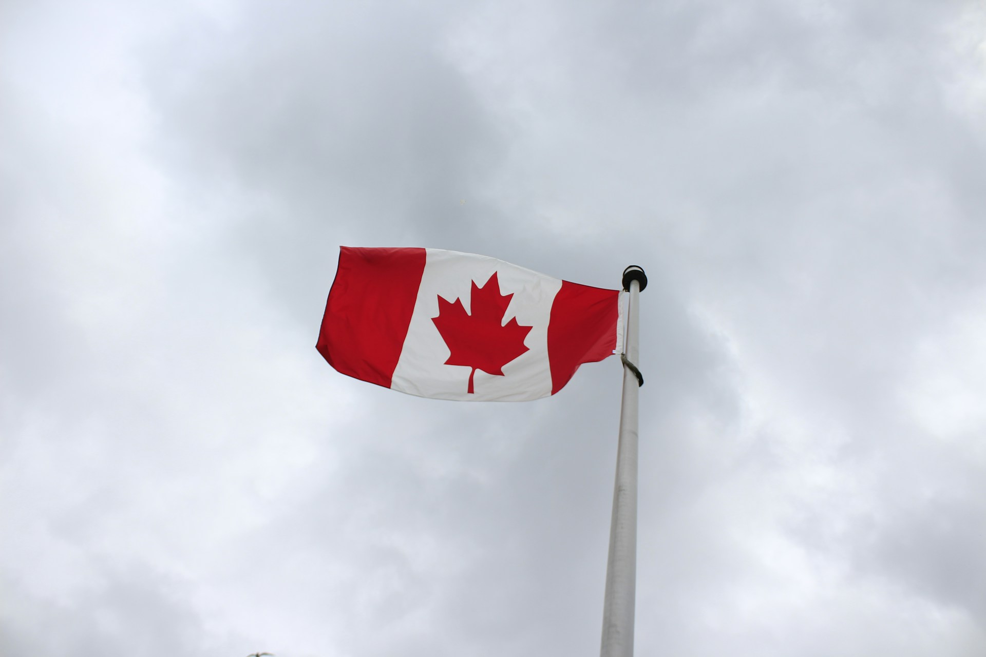 a canadian flag flying in the wind on a cloudy day