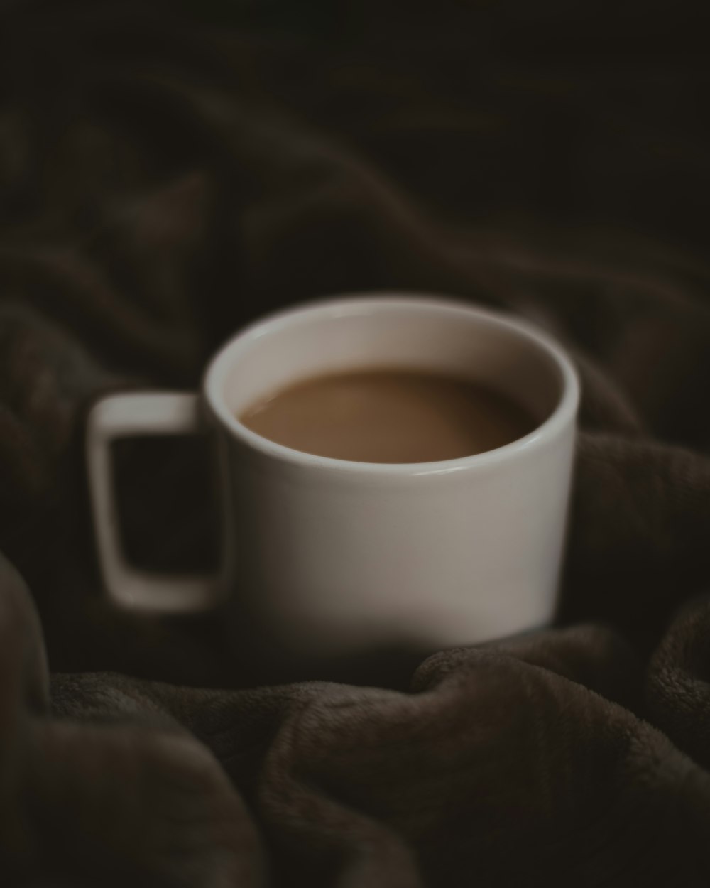 a cup of coffee sitting on top of a blanket