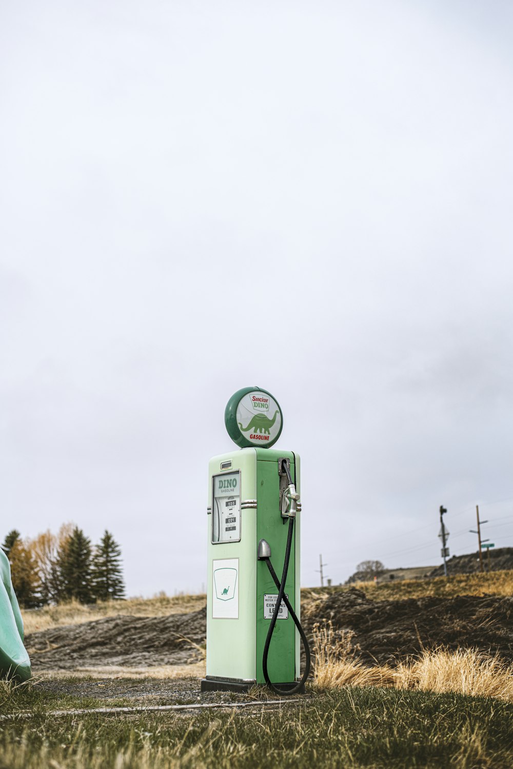 una pompa di benzina verde seduta in cima a un campo coperto di erba