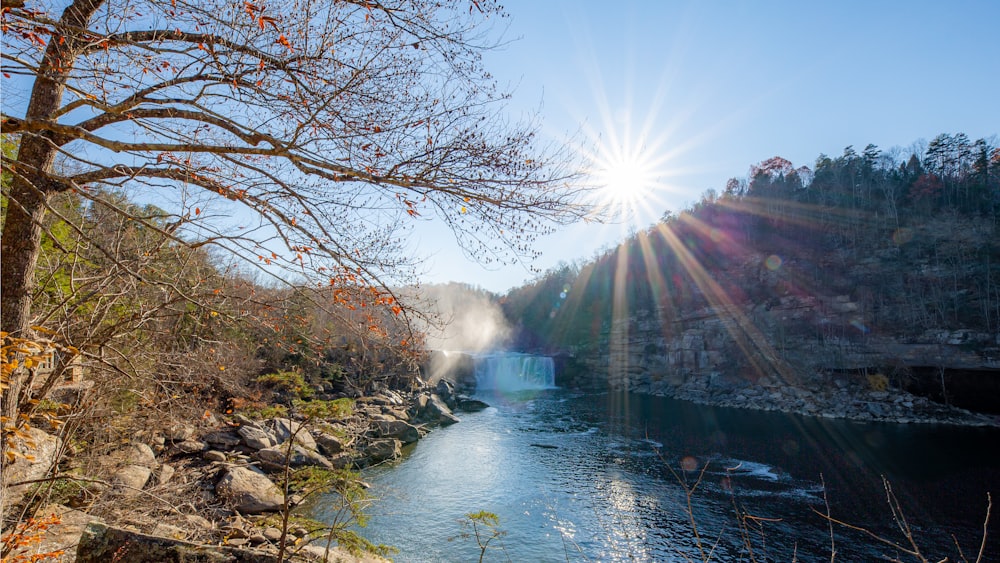 the sun shines brightly over a river and waterfall