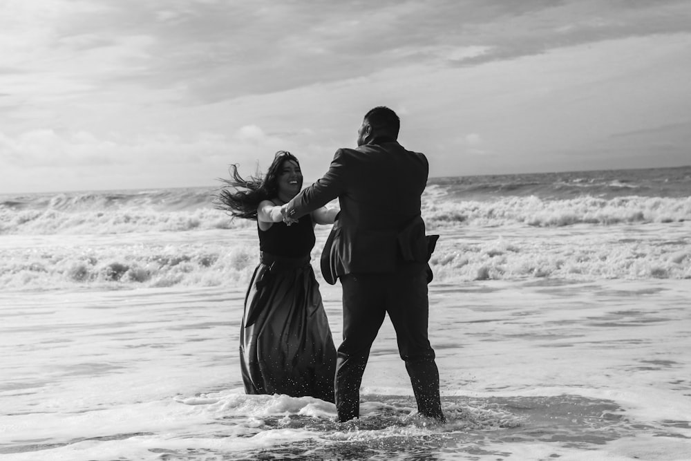 a man and a woman standing in the ocean holding hands