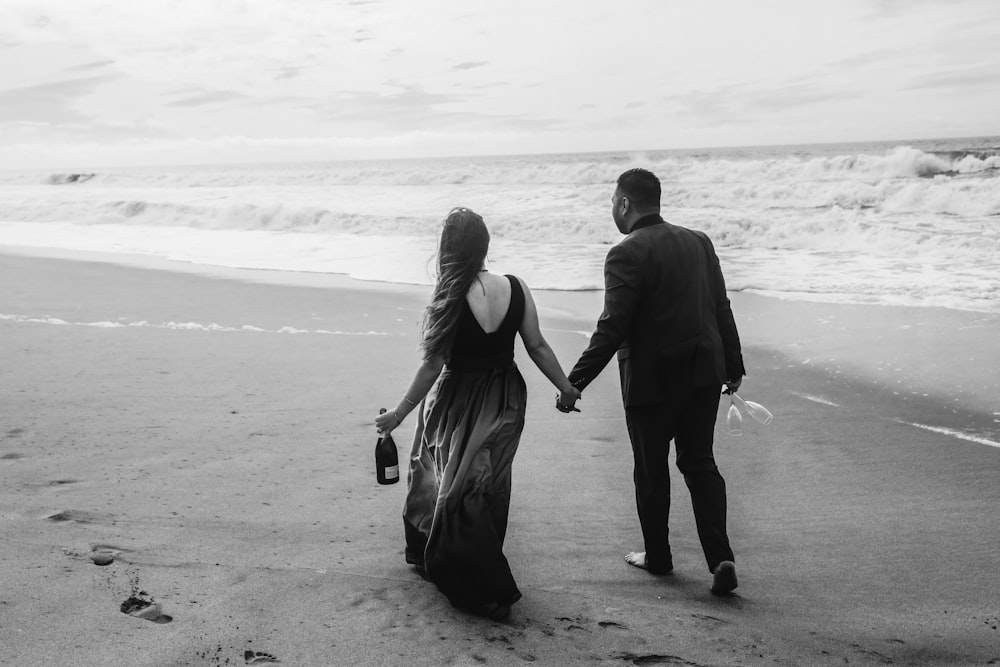 a man and a woman walking on a beach holding hands