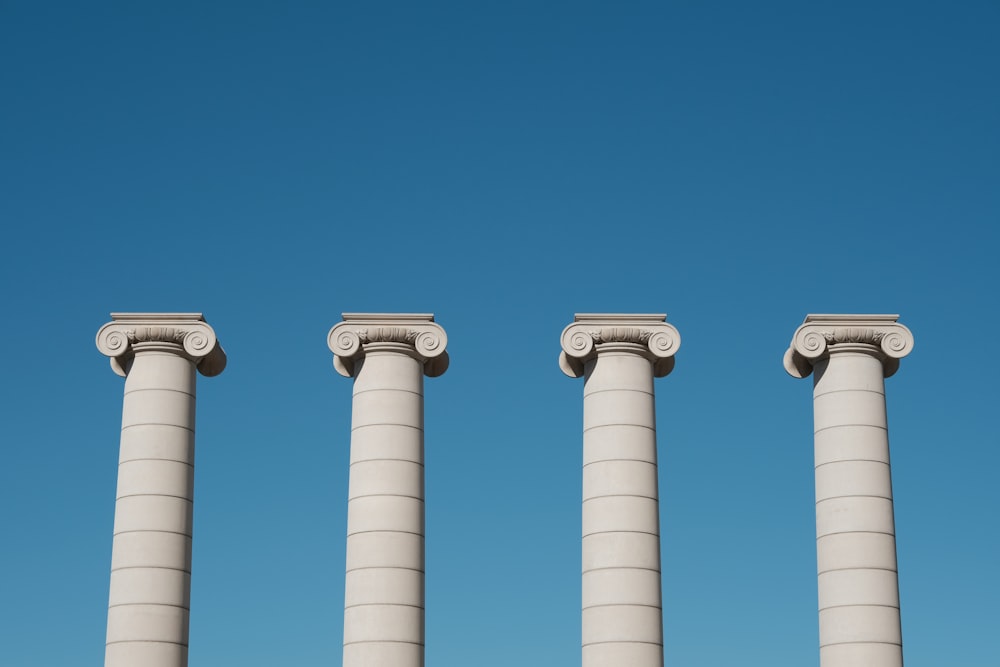 a row of white pillars against a blue sky