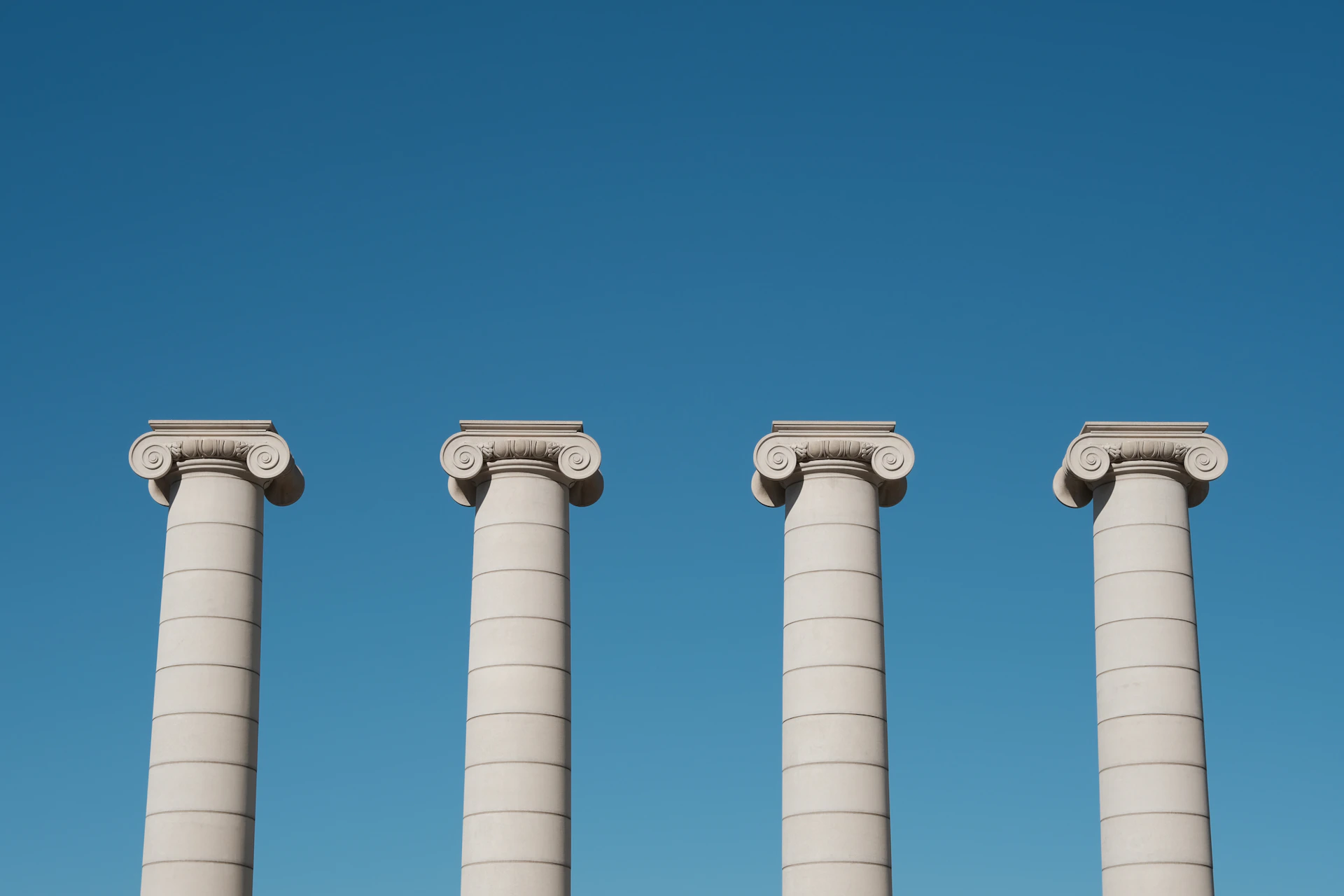 a row of white pillars against a blue sky