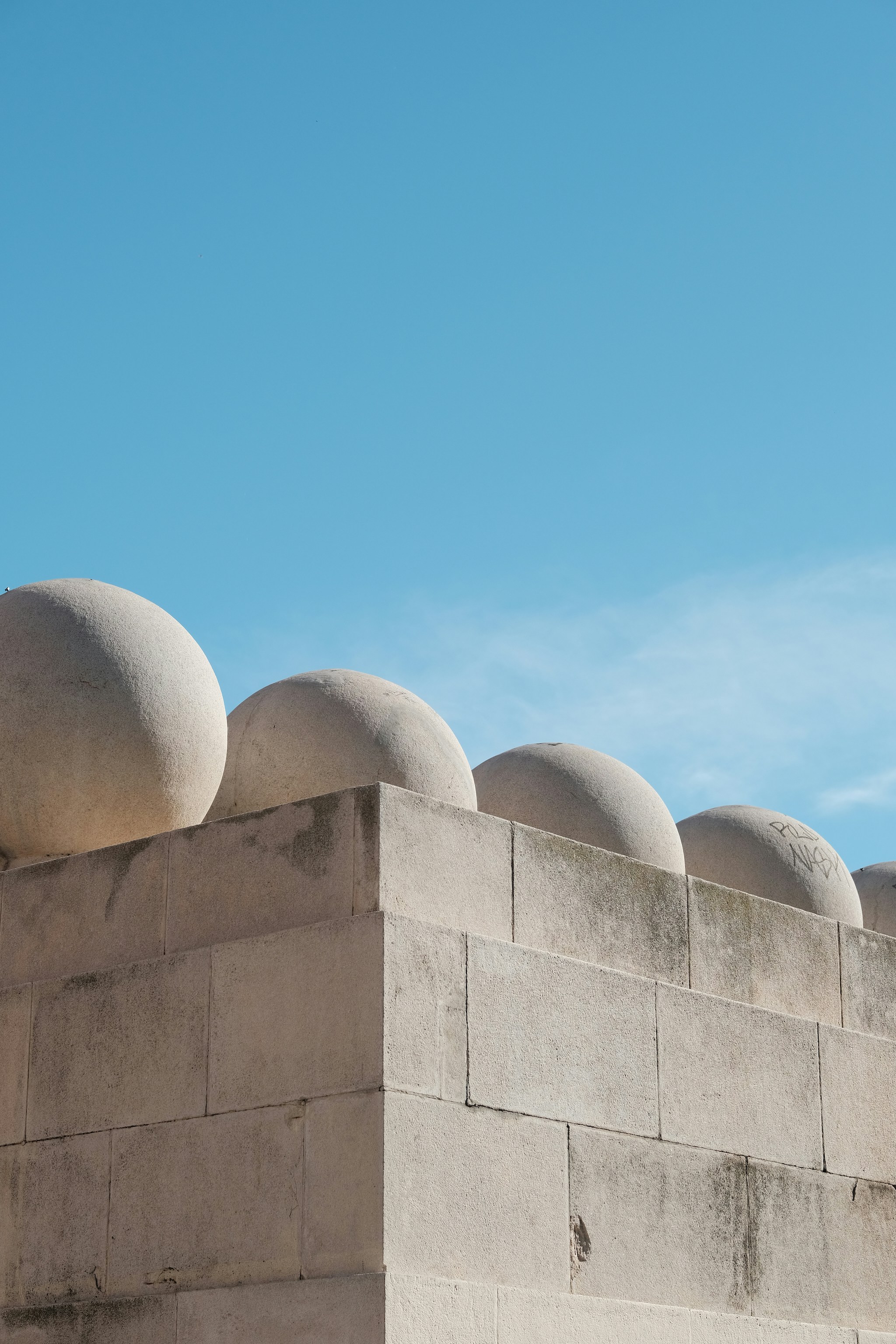 A light grey concrete wall with smooth, spherical concrete elements on top.