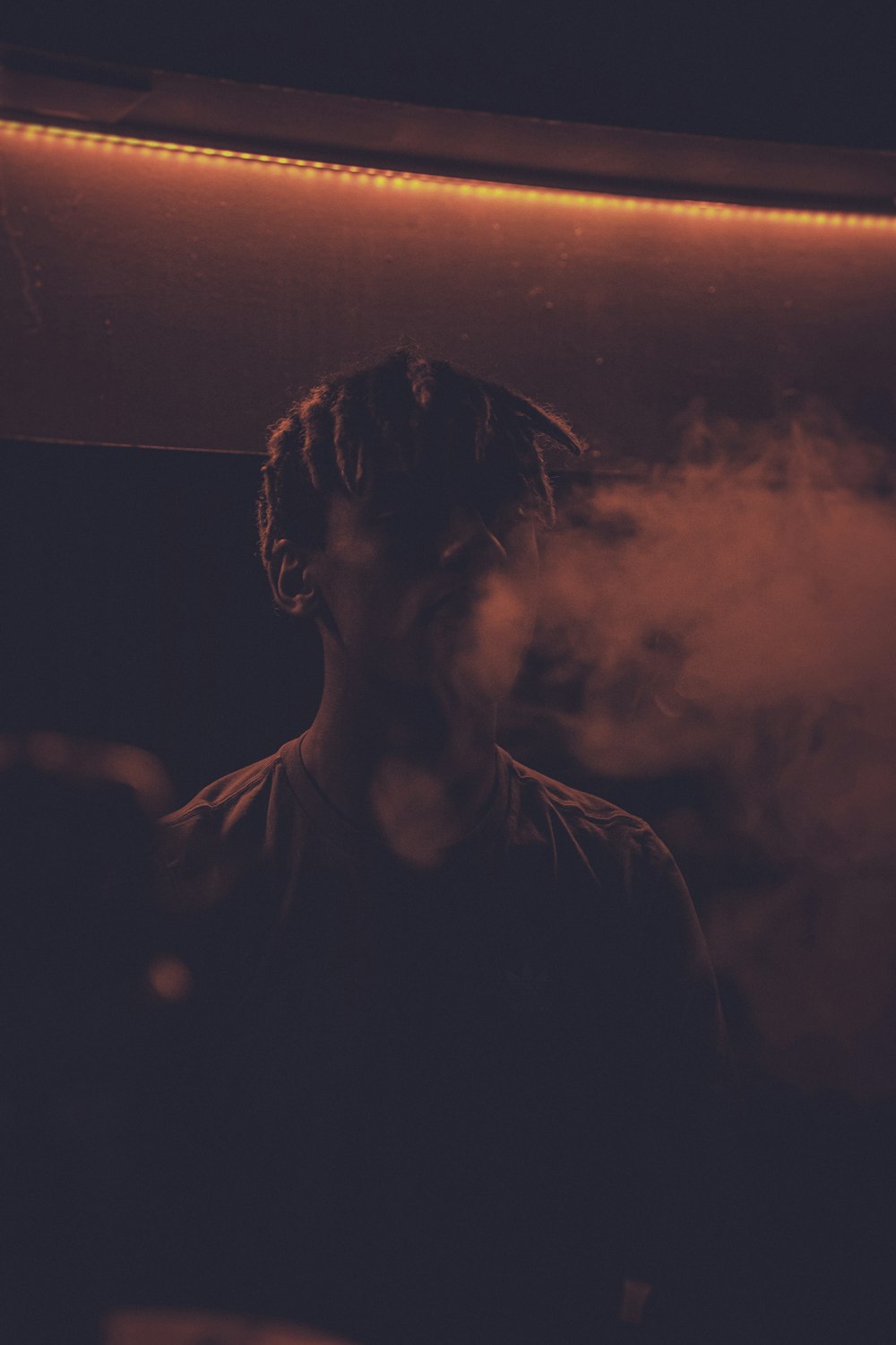 a man with dreadlocks standing in a dark room