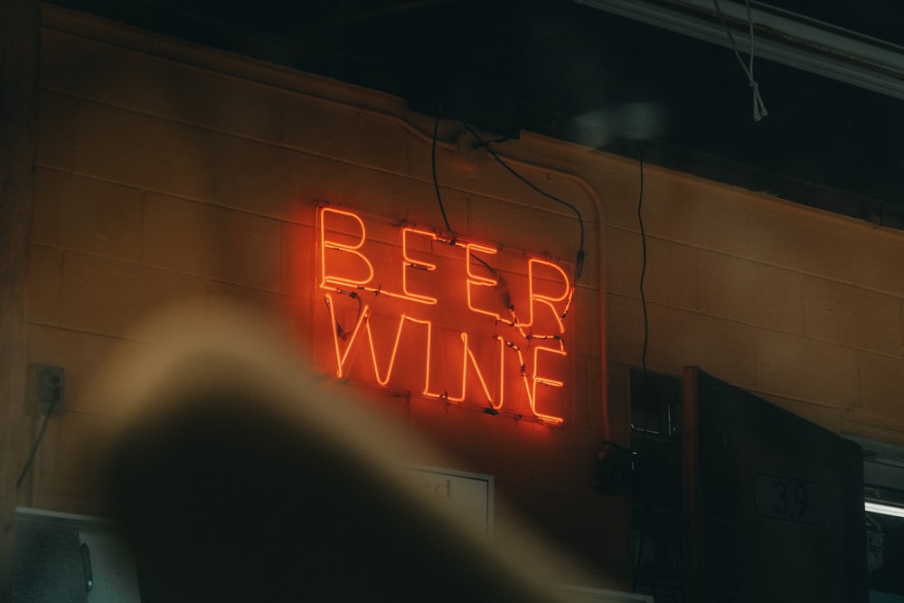 a neon sign that says beer wine on the side of a building