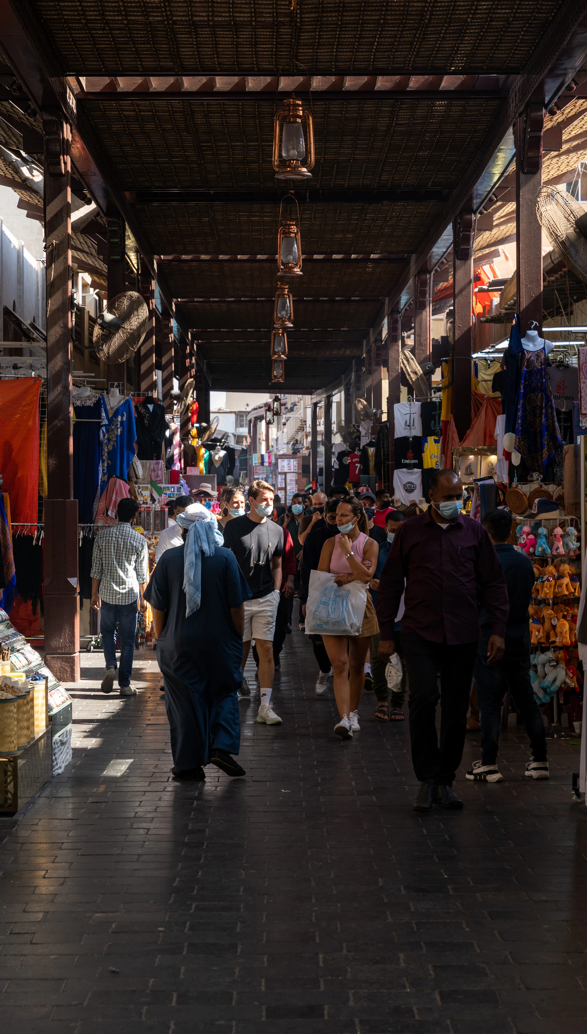 People walk through a busy marketplace with stalls.