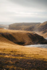 Rolling hills and rugged cliffs along the Australian coastline at golden hour.