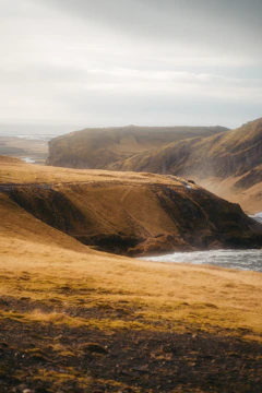 Rolling hills and rugged cliffs along the Australian coastline at golden hour.