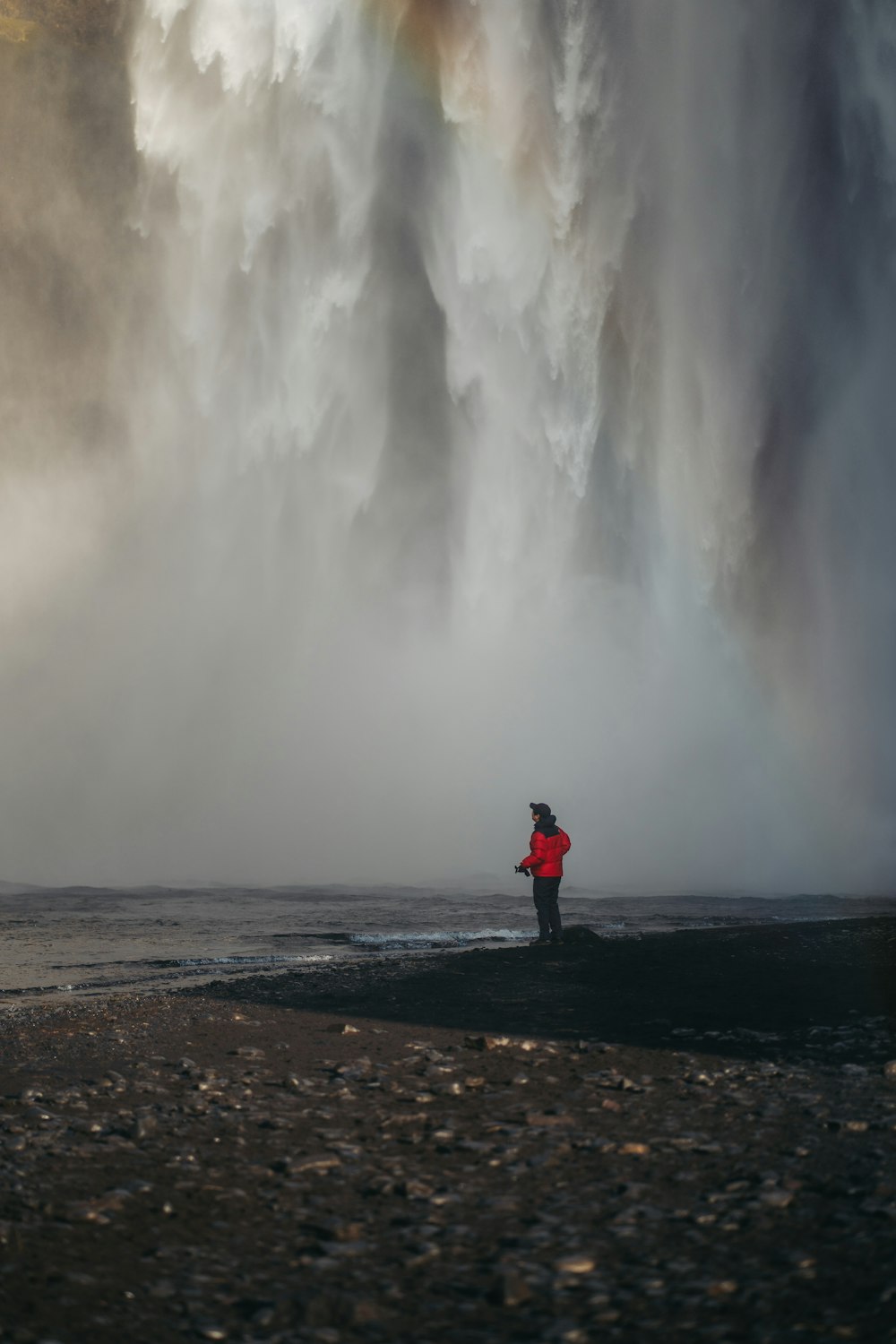 una persona in piedi di fronte a una grande cascata