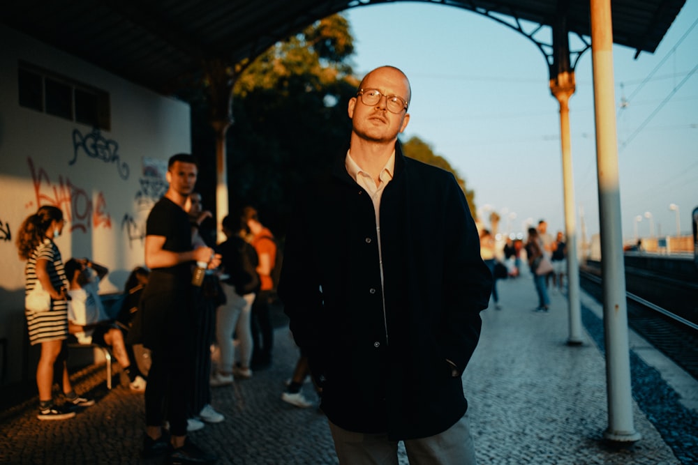 a man standing on a train platform next to a group of people