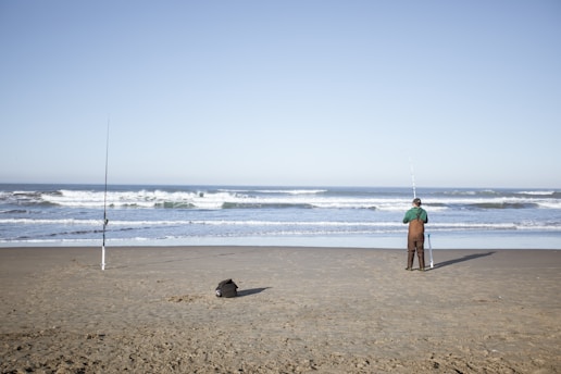 a man standing on top of a sandy beach next to the ocean