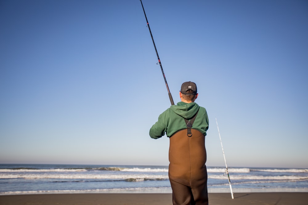 a man standing on a beach holding a fishing pole