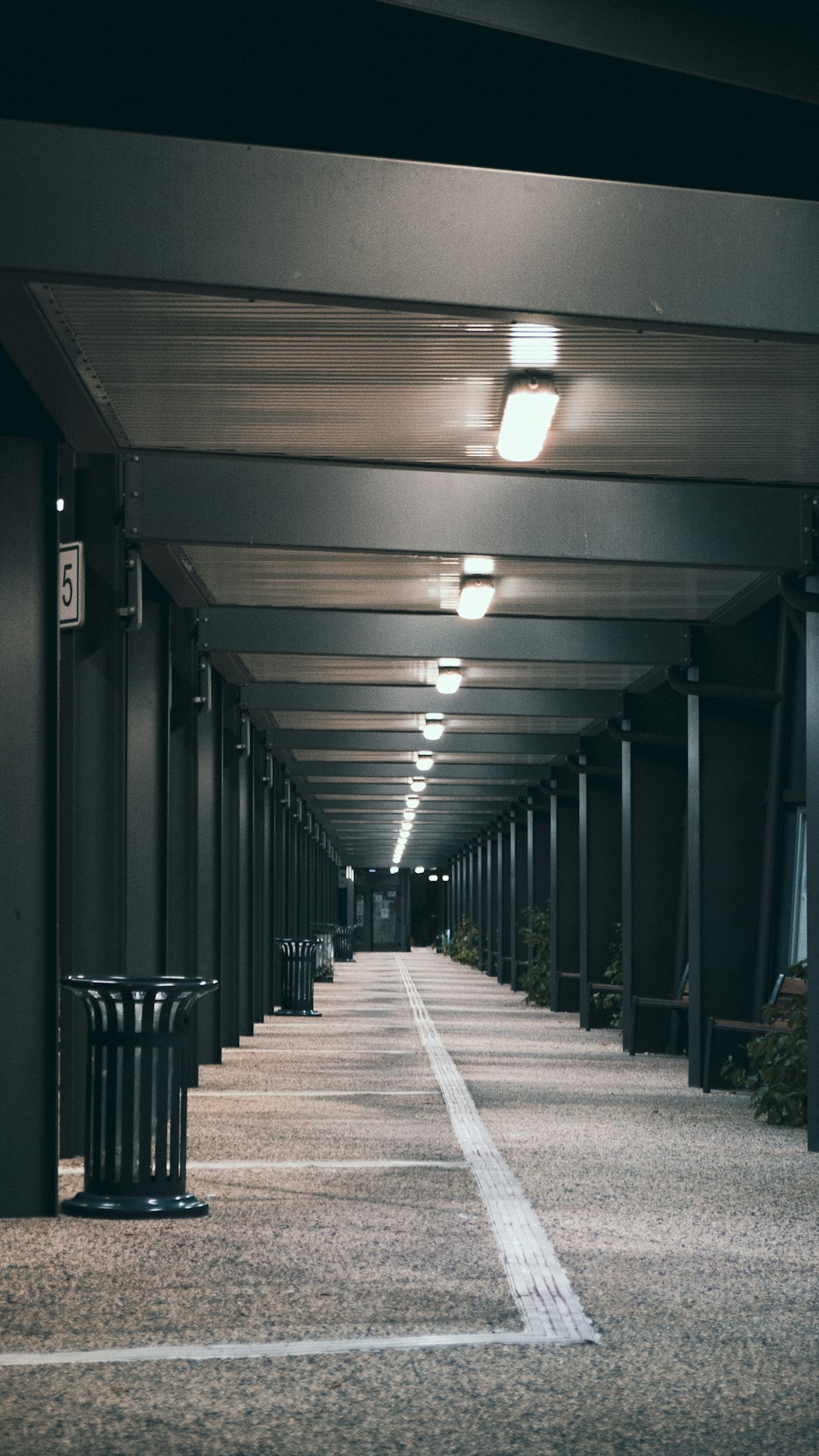 a long hallway with lights and a trash can