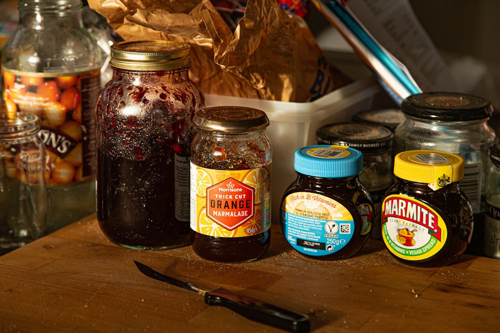 a wooden table topped with jars of food and a knife