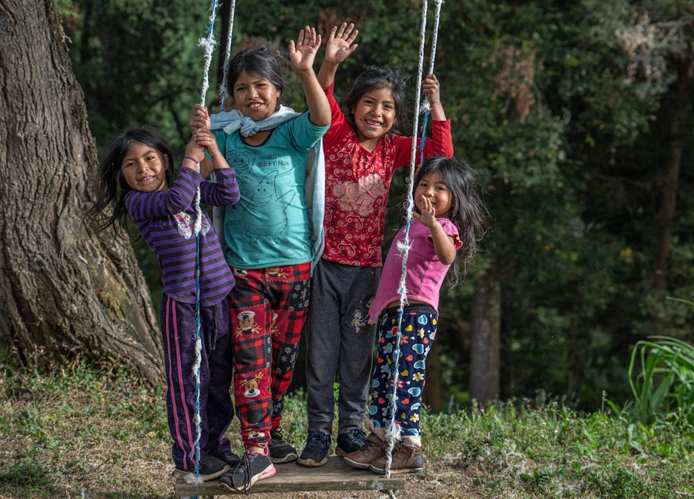 a group of young children standing next to each other on a swing