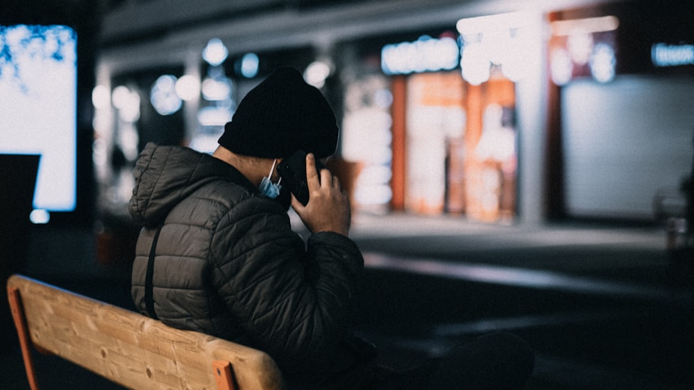 a person sitting on a bench talking on a cell phone