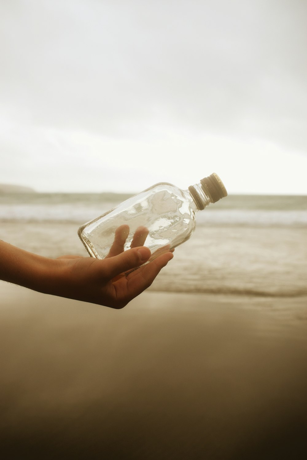 a person holding a bottle of water on a beach