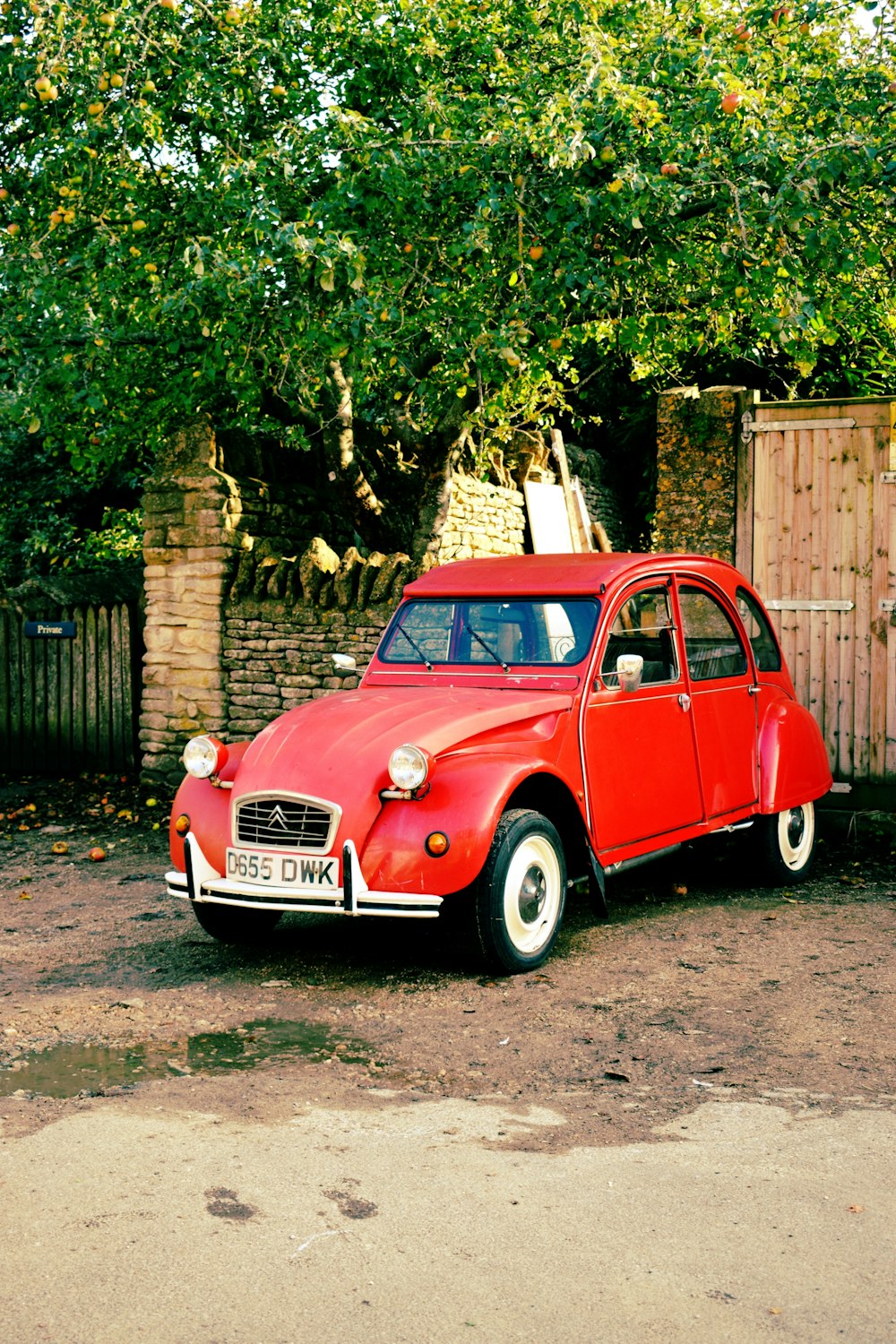 a red car parked in front of a wooden fence