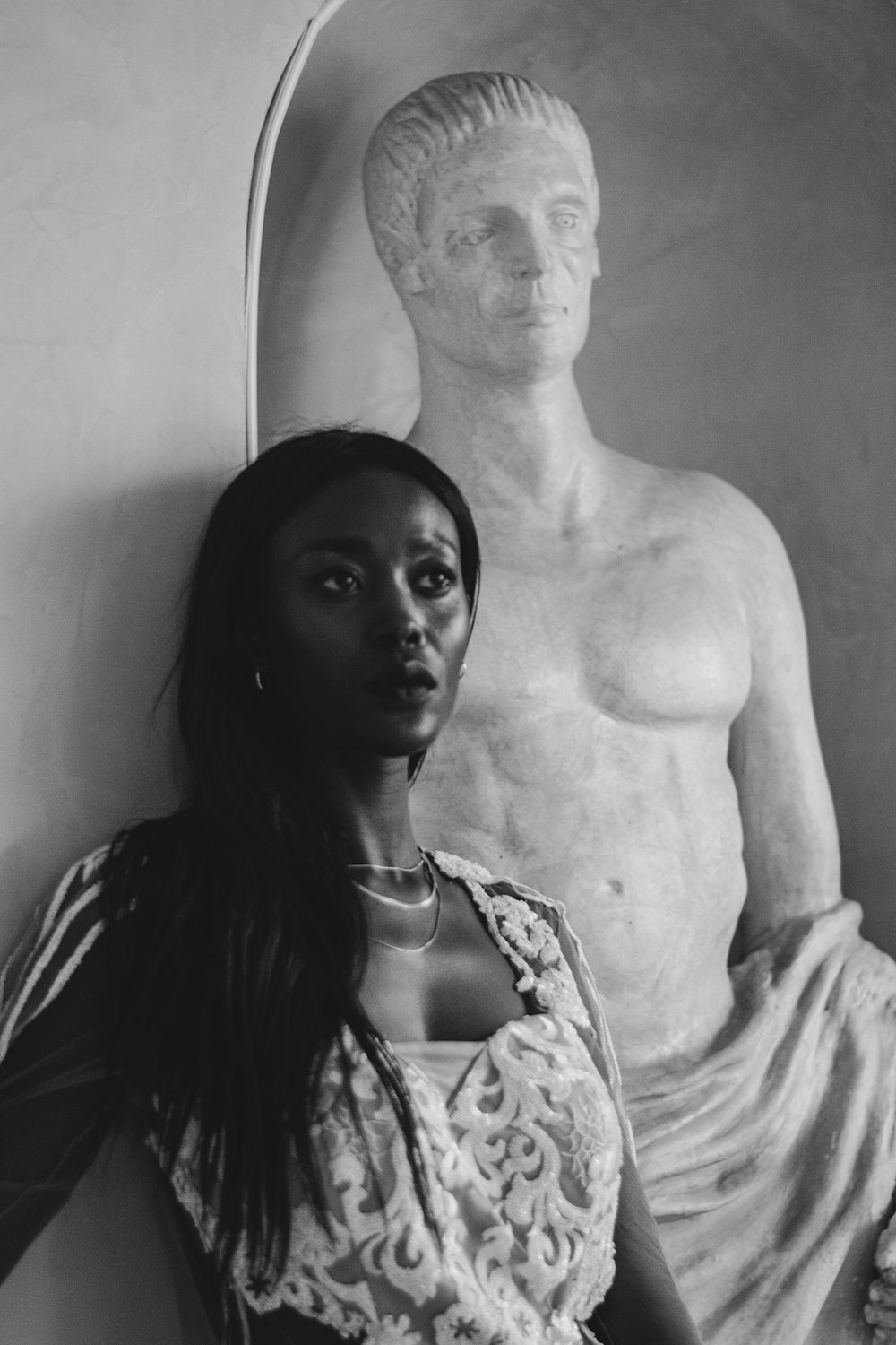 a black and white photo of a woman in front of a statue