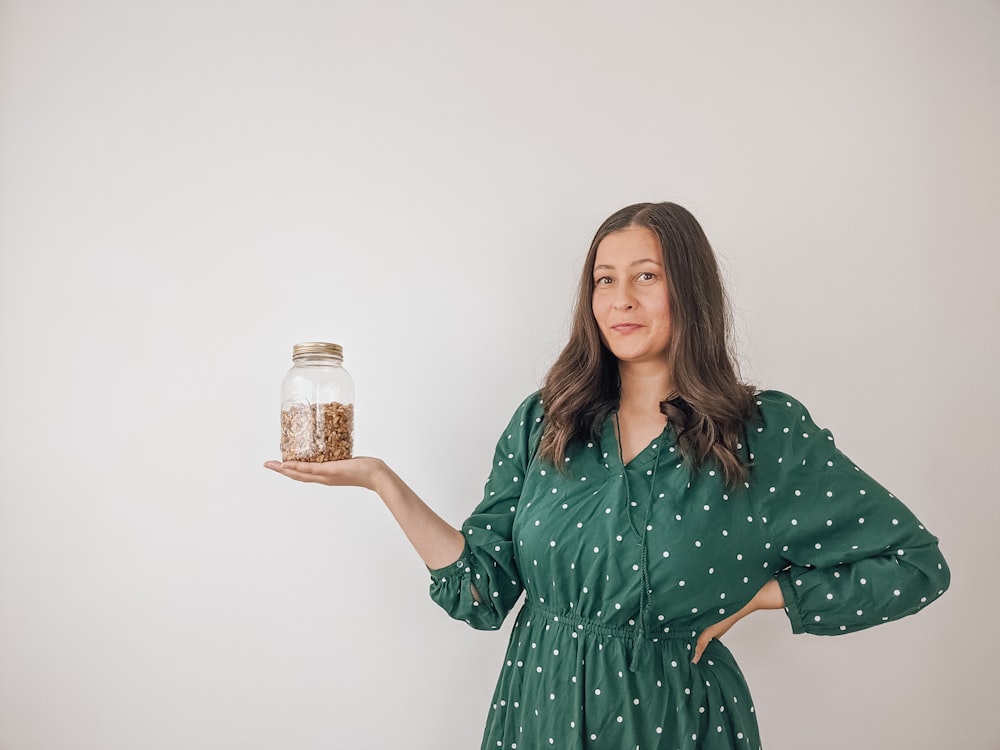 a woman holding a jar of food in her hand