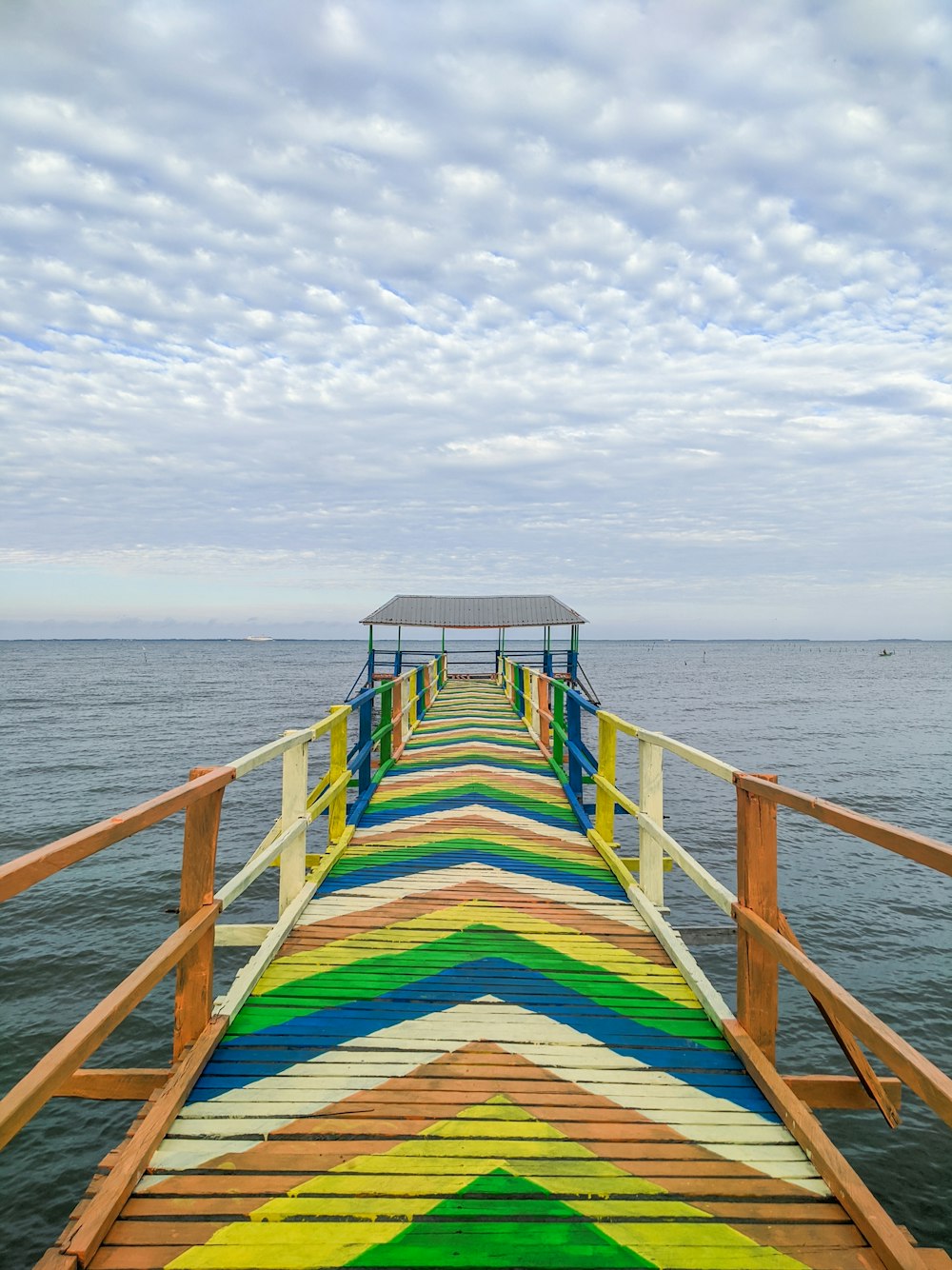 a pier with a painted walkway leading to the ocean